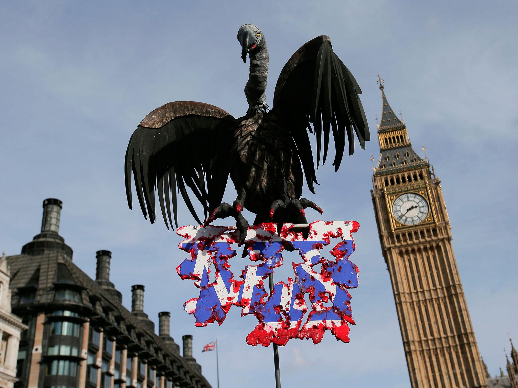 Protesters hold a placard with a model of a vulture during a march against private companies' involvement in the NHS