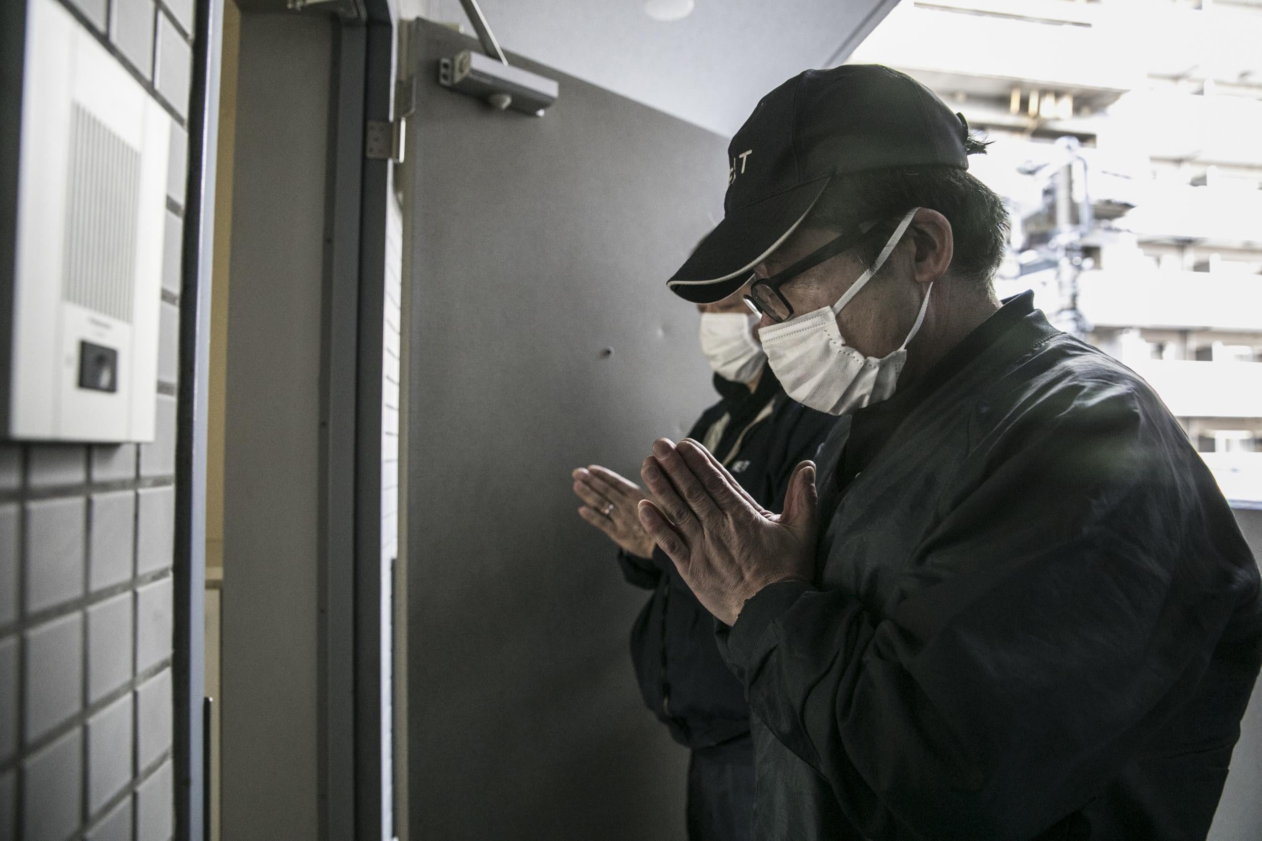 A cleaning firm prays after clearing out a flat, where a man had died about four months before his body was discovered (Shiho Fukada/Washington Post)