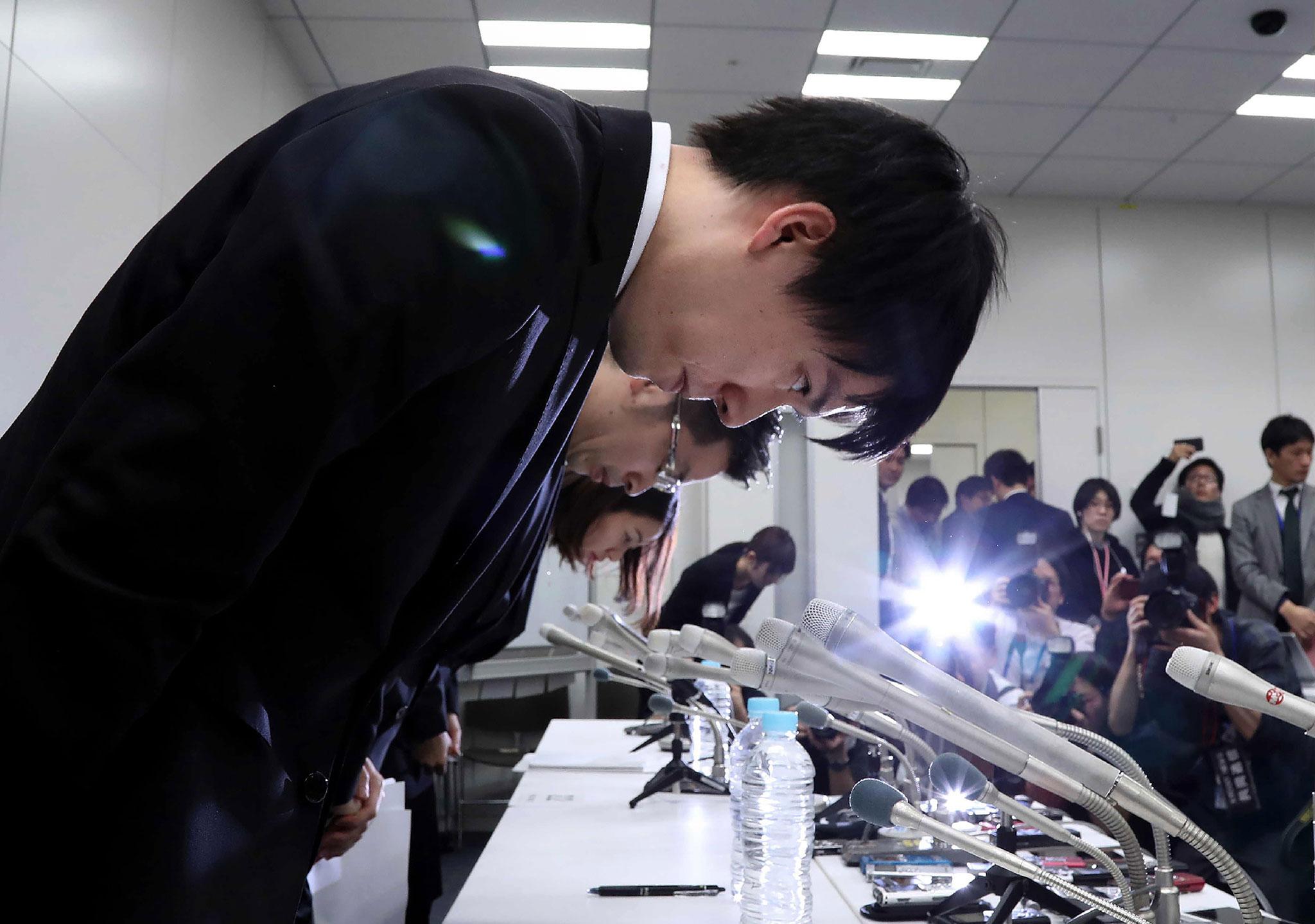 Coincheck president Koichiro Wada (left) bows in apology at the end a press conference in Tokyo