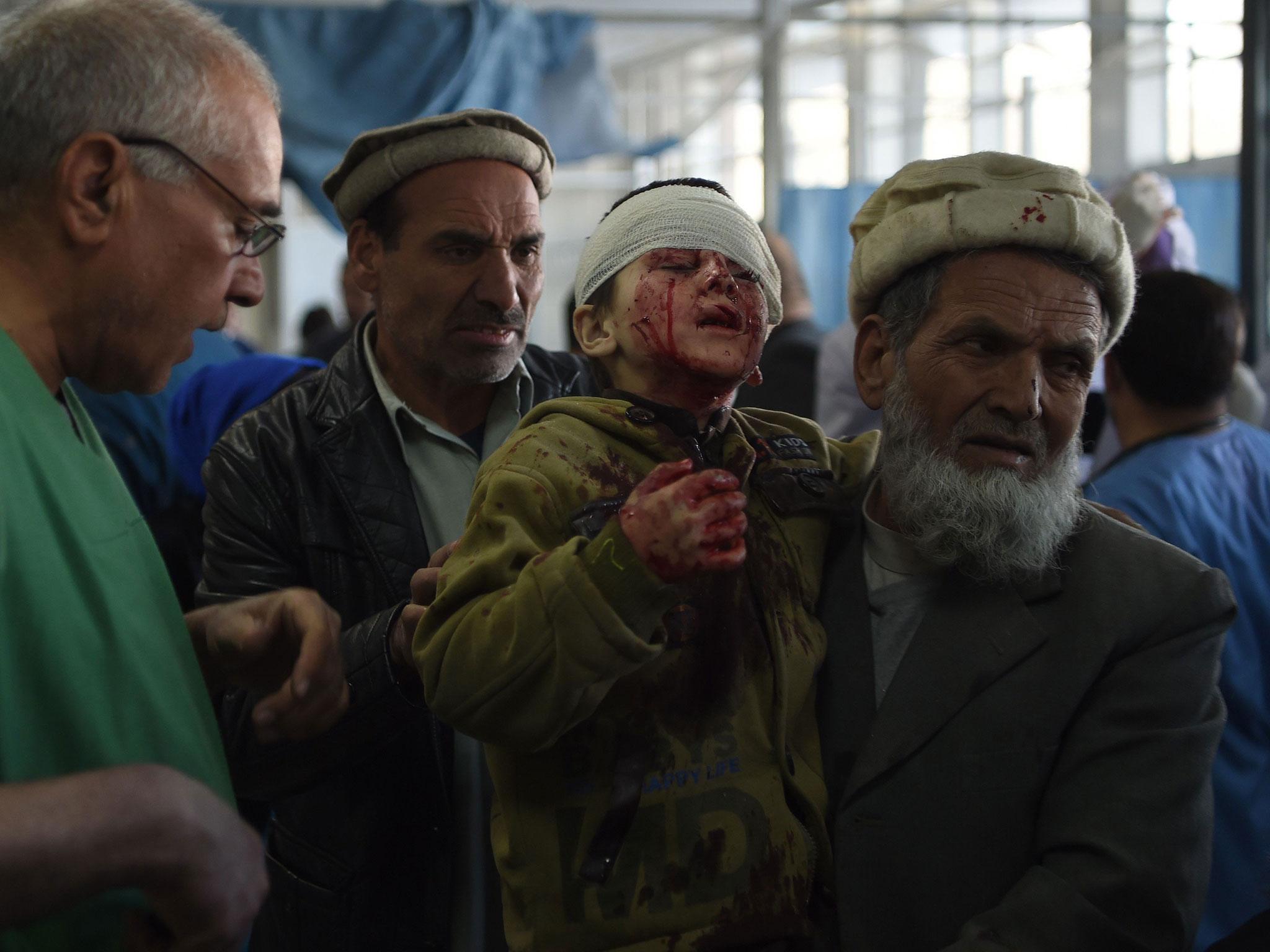 An Afghan man holds a wounded child, after a car bomb exploded near the old Interior Ministry building