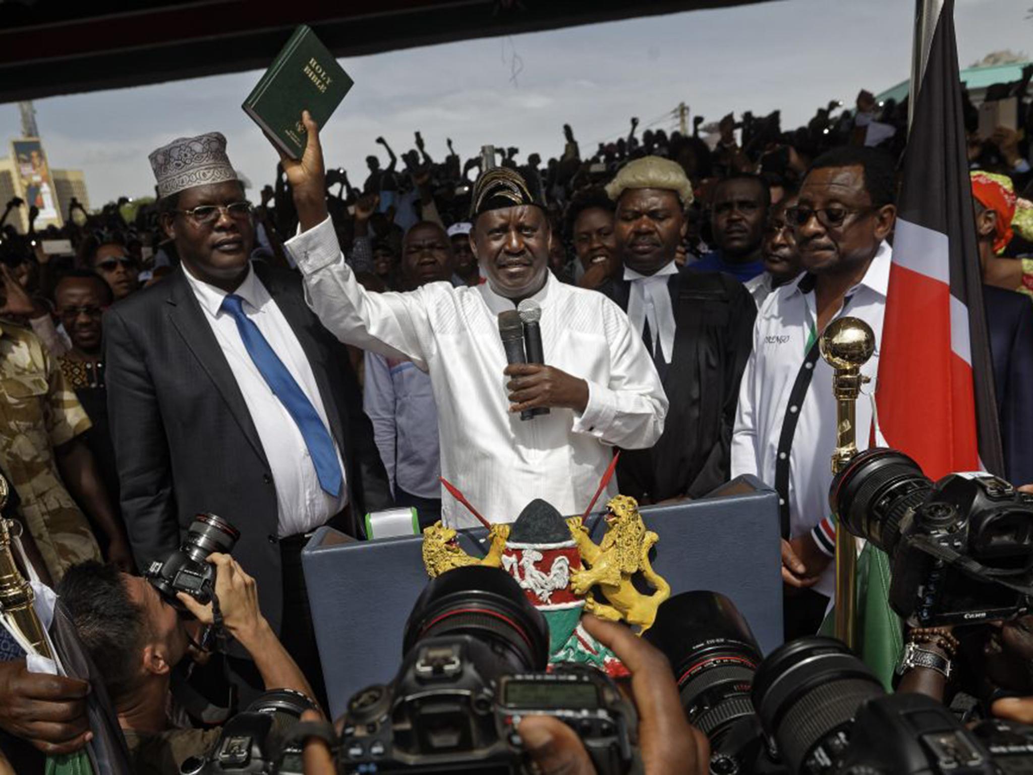 Opposition leader Raila Odinga holds a Bible aloft after swearing an oath during a mock swearing-in ceremony