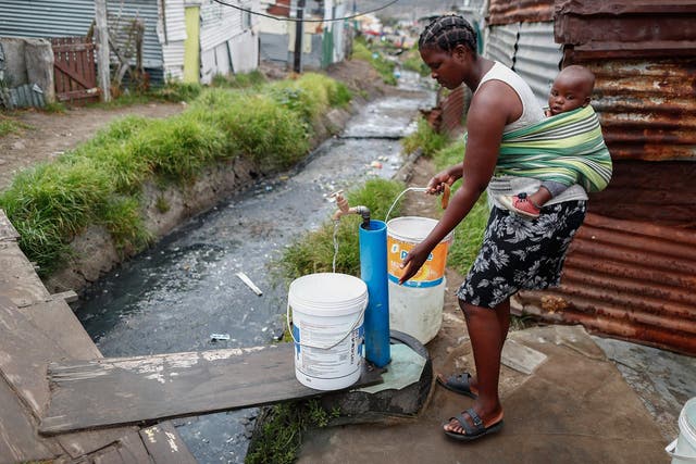 <p>A resident collects drinking water from a communal municipal tap in Cape Town, South Africa</p>