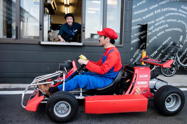 Participants in Mario costume drives through McDonald's drive-thru for the Real Mario Kart event in Tokyo on November 16, 2014 in Tokyo, Japan