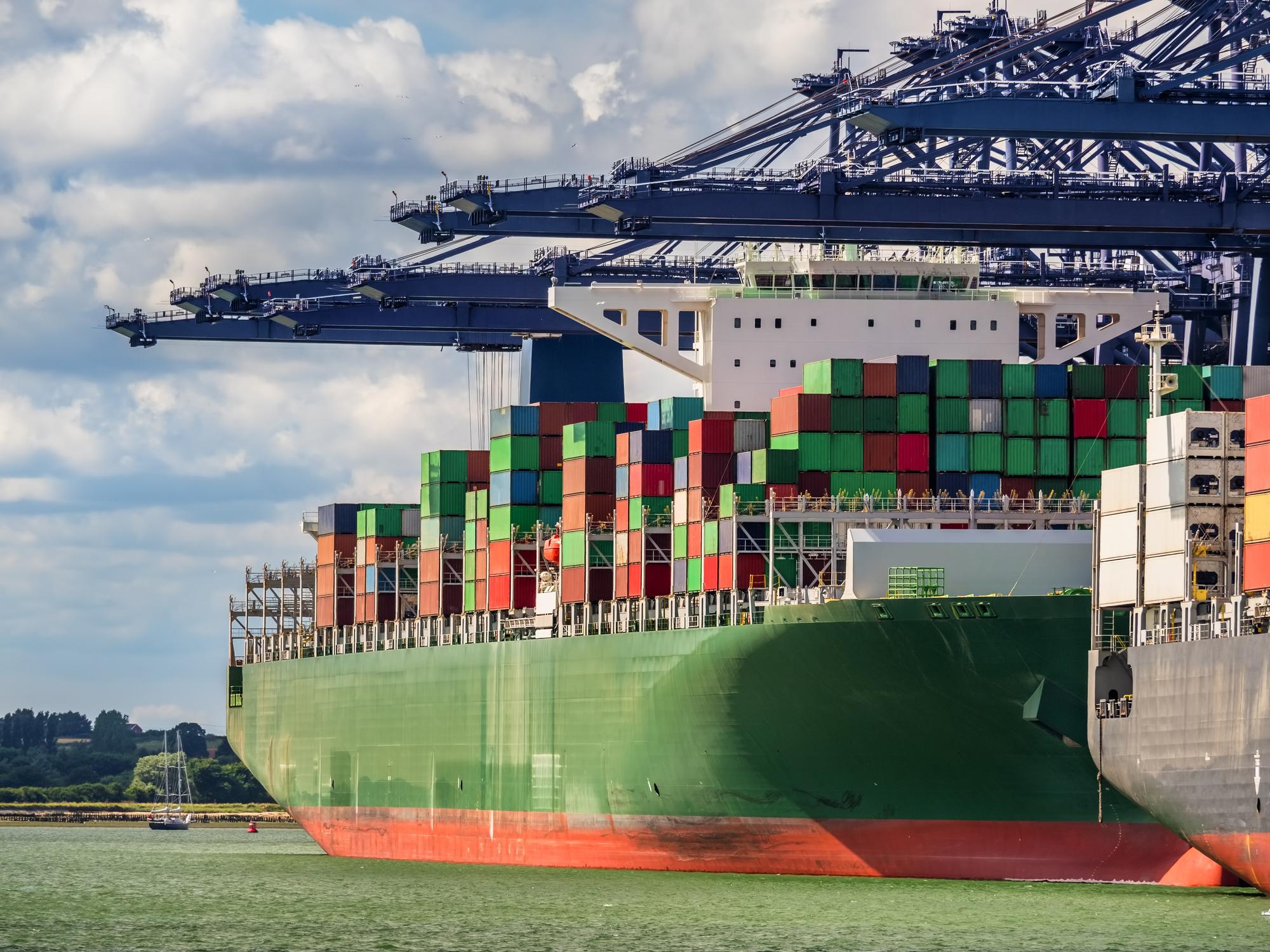 Huge green container ship under loading operation with blue gantry cranes in the port of Felixtowe