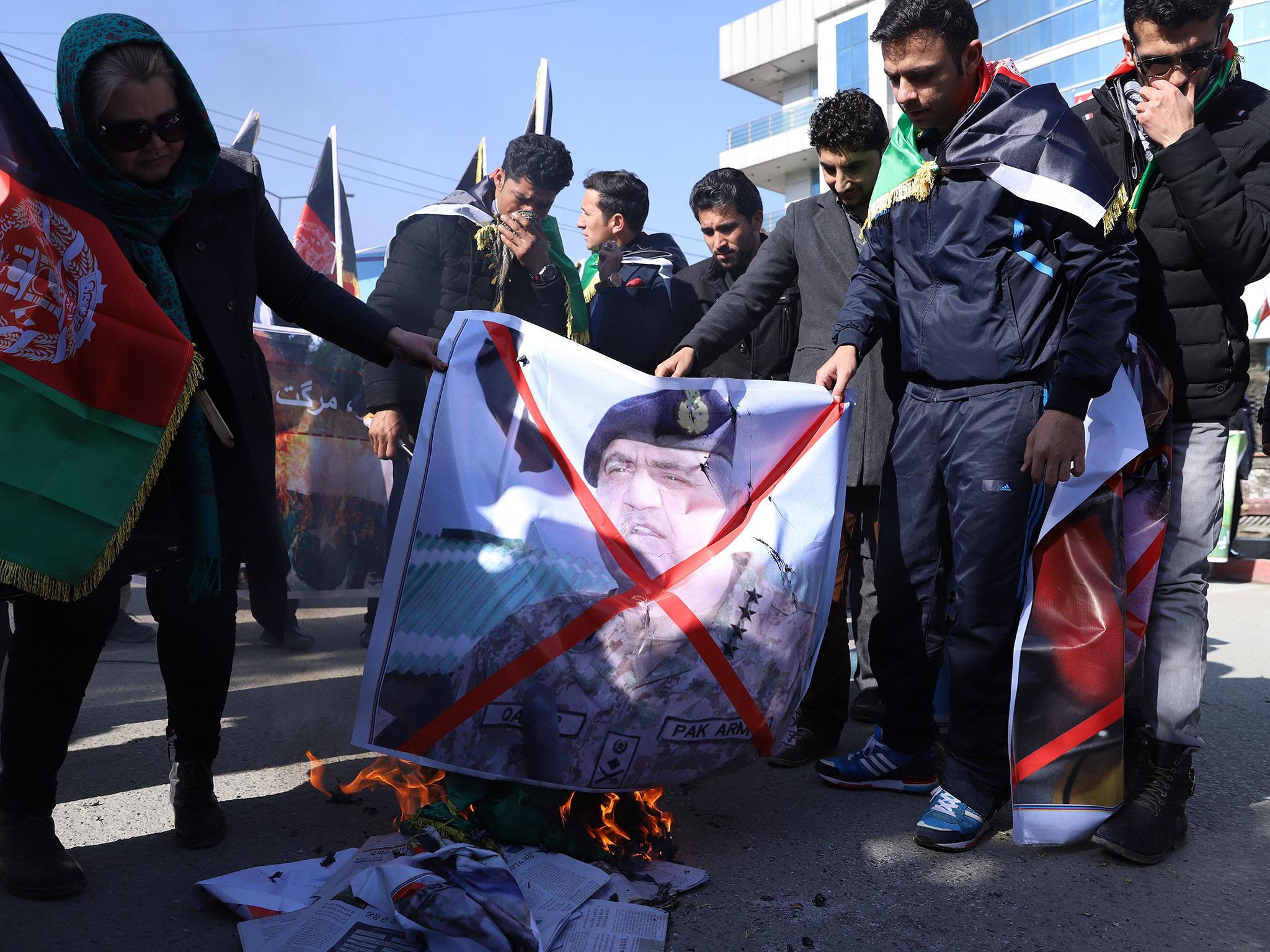 Afghan protesters burn a picture of Pakistan’s chief of army staff during a demonstration in Kabul