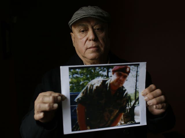 Miguel Perez poses as he holds a photo of his son Miguel Perez Jr, in Chicago, Illinois