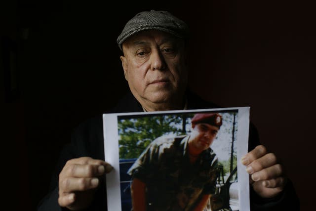 Miguel Perez poses as he holds a photo of his son Miguel Perez Jr, in Chicago, Illinois