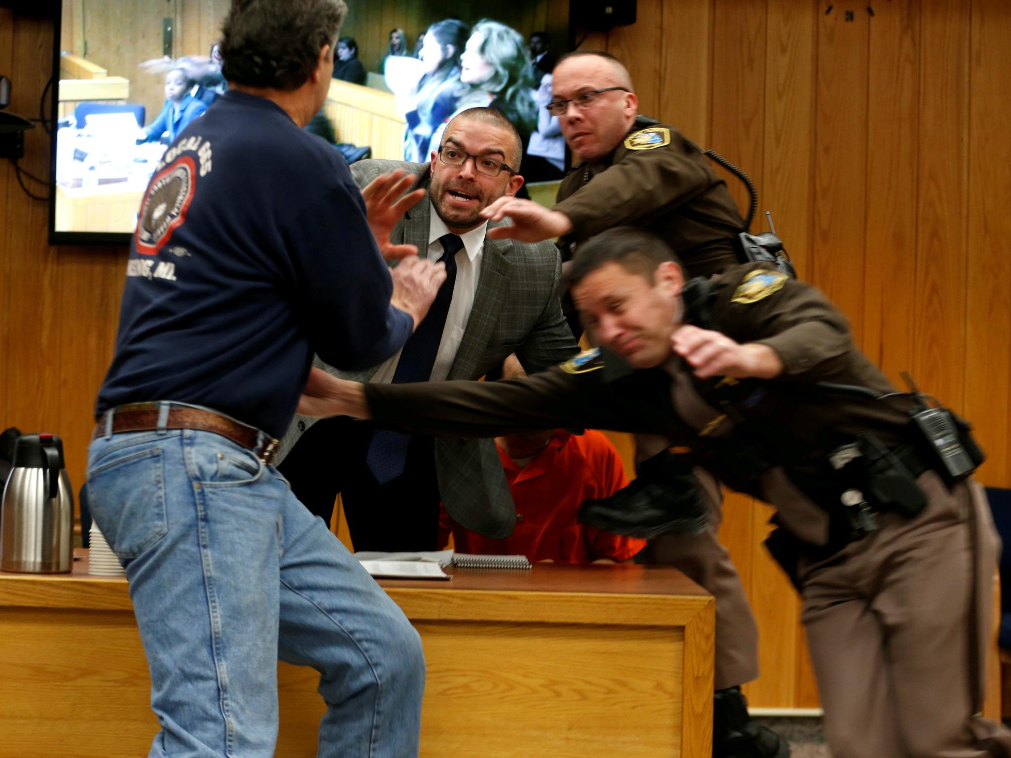 Randall Margraves (L) lunges at Larry Nassar (wearing orange) a former team USA Gymnastics doctor on 2 February 2018. Nassar has been sentenced to more than 175 years in jail.