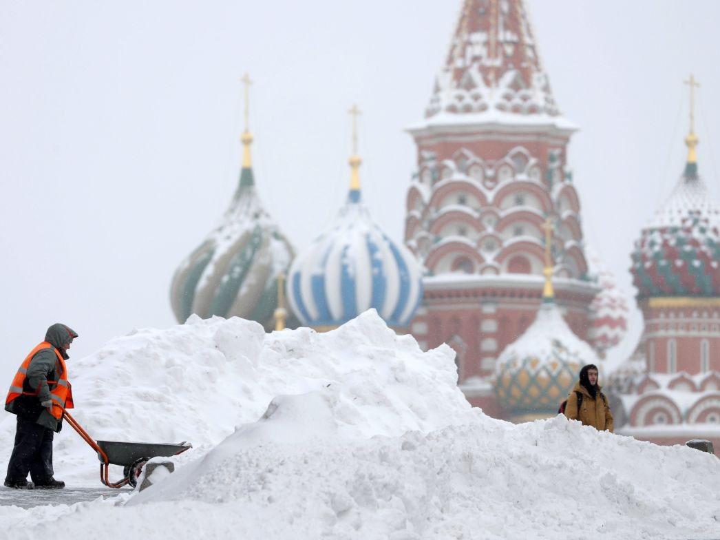 Moscow resident attempting to shovel snow near St Basil's Cathedral