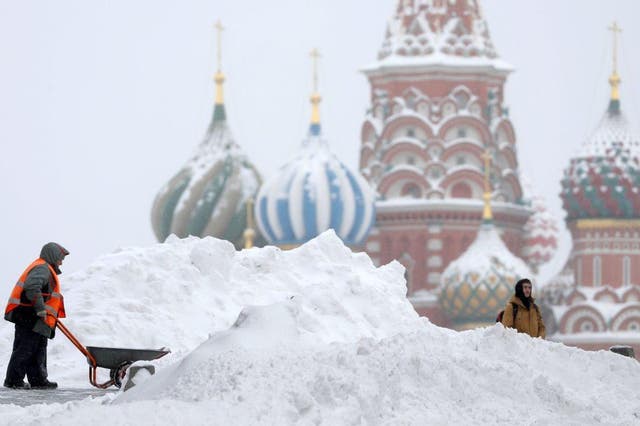 Moscow resident attempting to shovel snow near St Basil's Cathedral