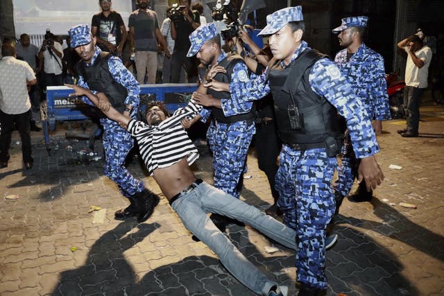 Police officers detain an opposition protester in Male, Maldives