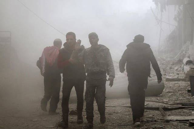 An injured man walks through the dust after a reported air strike in the rebel-held town of Saqba, in the besieged Eastern Ghouta region on the outskirts of the capital Damascus