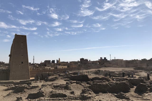 An ancient Egyptian excavation site at Tell Edfu, with the temple of Horus and the modern town of Edfu in the background