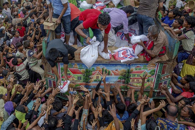 Rohingya Muslims reach out for food distributed by aid agencies near the Balukhali refugee camp in Cox’s Bazar