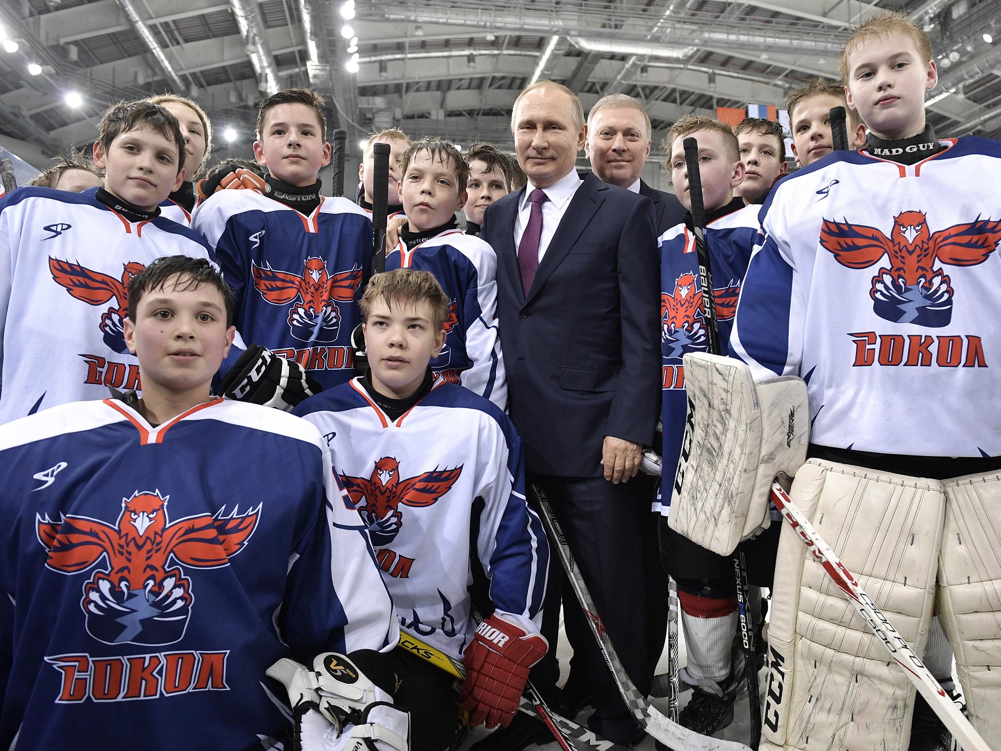 Vladimir Putin and Alliance Group president Musa Bazhayev pose with members of the Sokol Krasnoyarsk junior ice hockey team in Krasnoyarsk