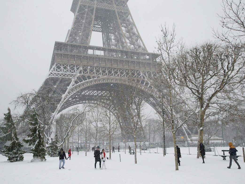 People stroll on the snow-covered Champ de Mars during a snowfall in Paris, France, on Friday, 9 February