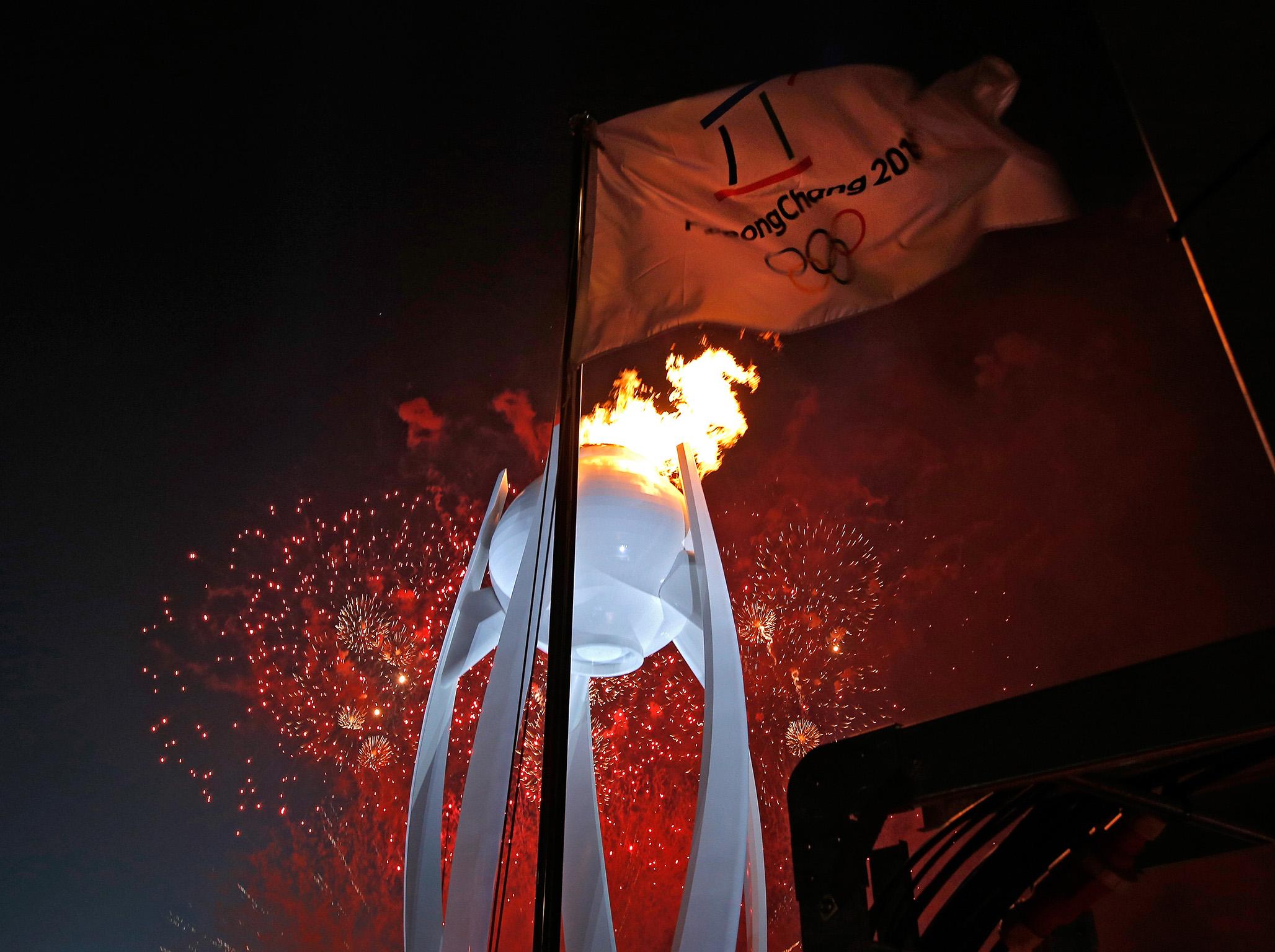 Fireworks erupt as the Olympic cauldron burns during the opening ceremony