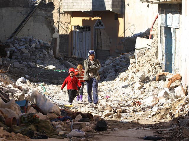 Iraqi children walk in a debris-strewn alleyway in Mosul's Old City on January 8, 2018, as a few people venture to return to the area.