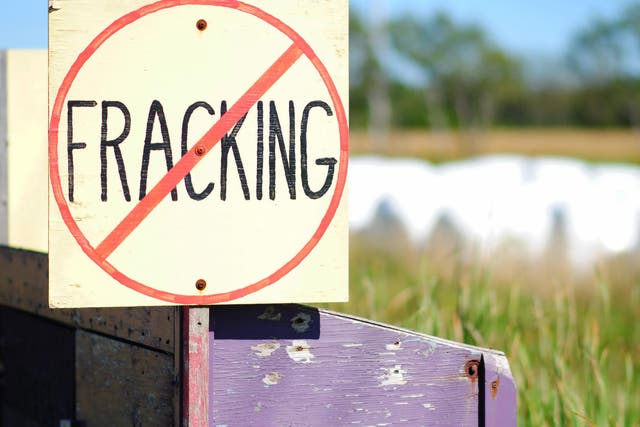 Hand-painted No Fracking Sign in Rural Setting, farmland and hay bales in background