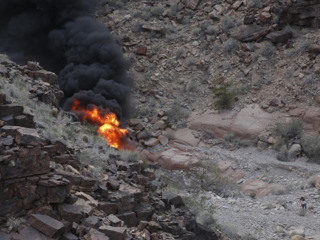 A survivor, bottom right, walks away from the scene of a deadly tour helicopter crash along the jagged rocks of the Grand Canyon in Arizona