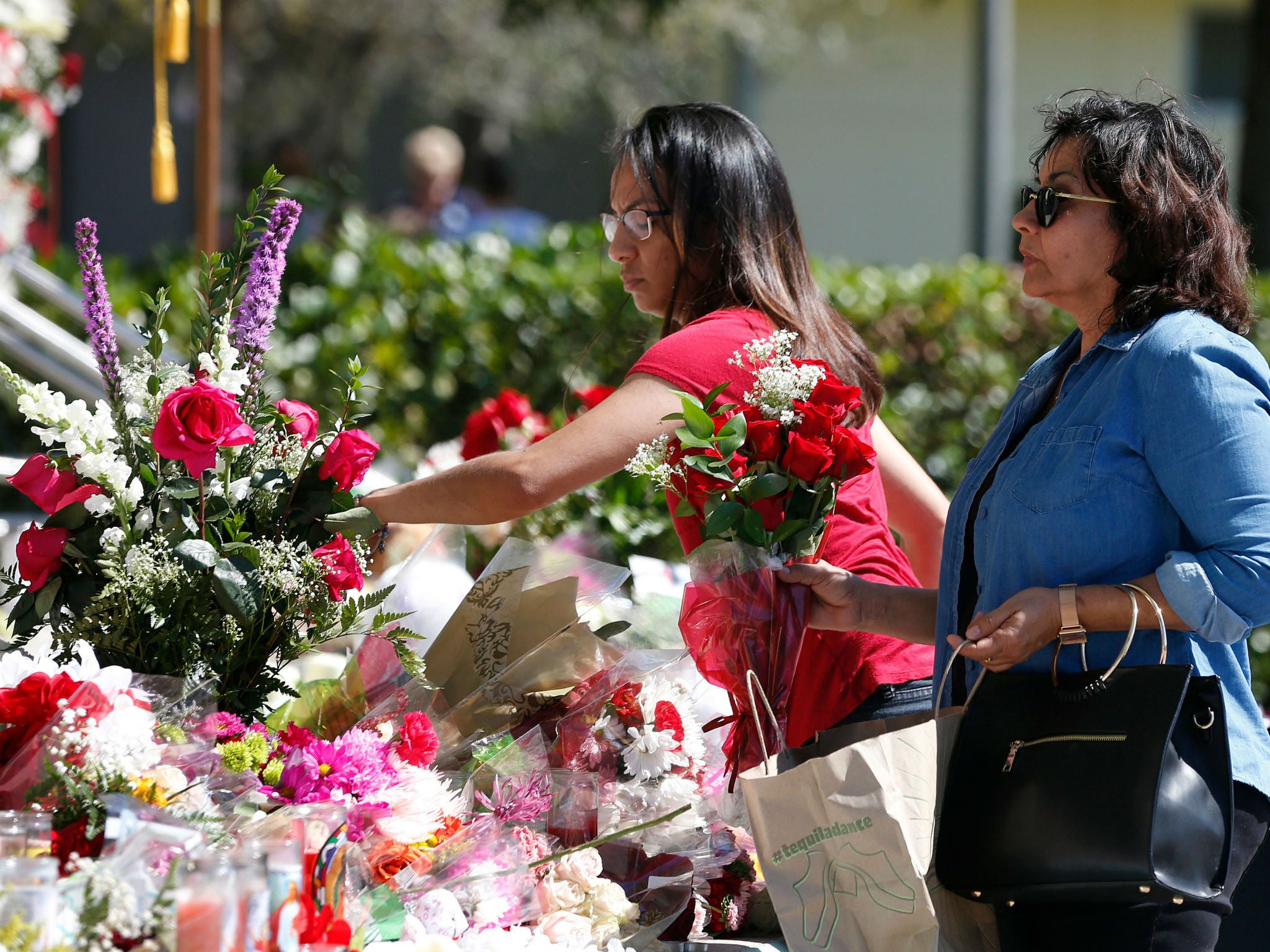 Mourners place flowers on a memorial for the victims of the Marjory Stoneman Douglas High School shooting in a park in Parklan