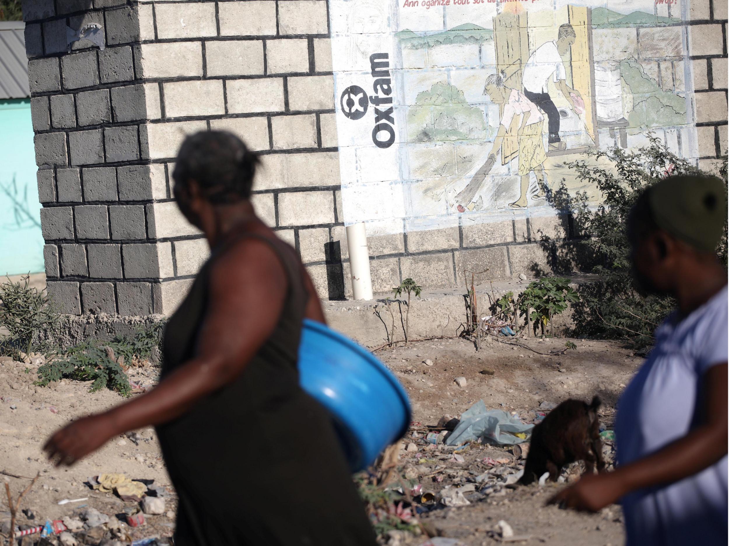 People walk past an Oxfam sign in Corail, a camp for people displaced after 2010 earthquake, on the outskirts of Port-au-Prince, Haiti