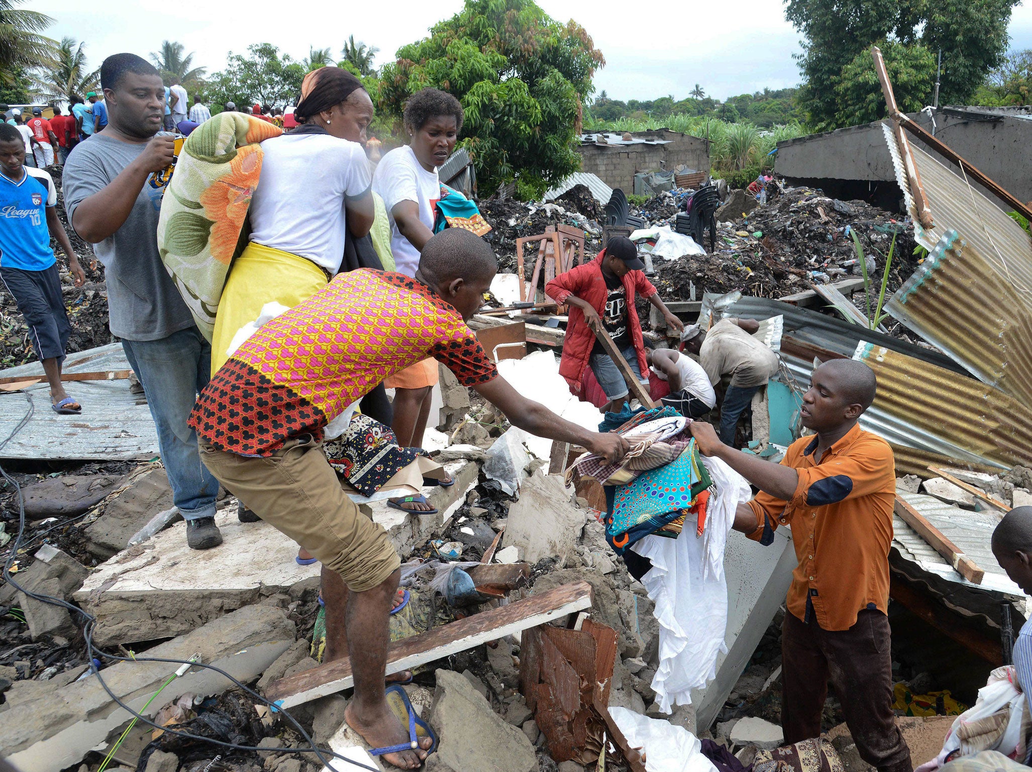 People look for their belongings under collapsed garbage piles in Maputo