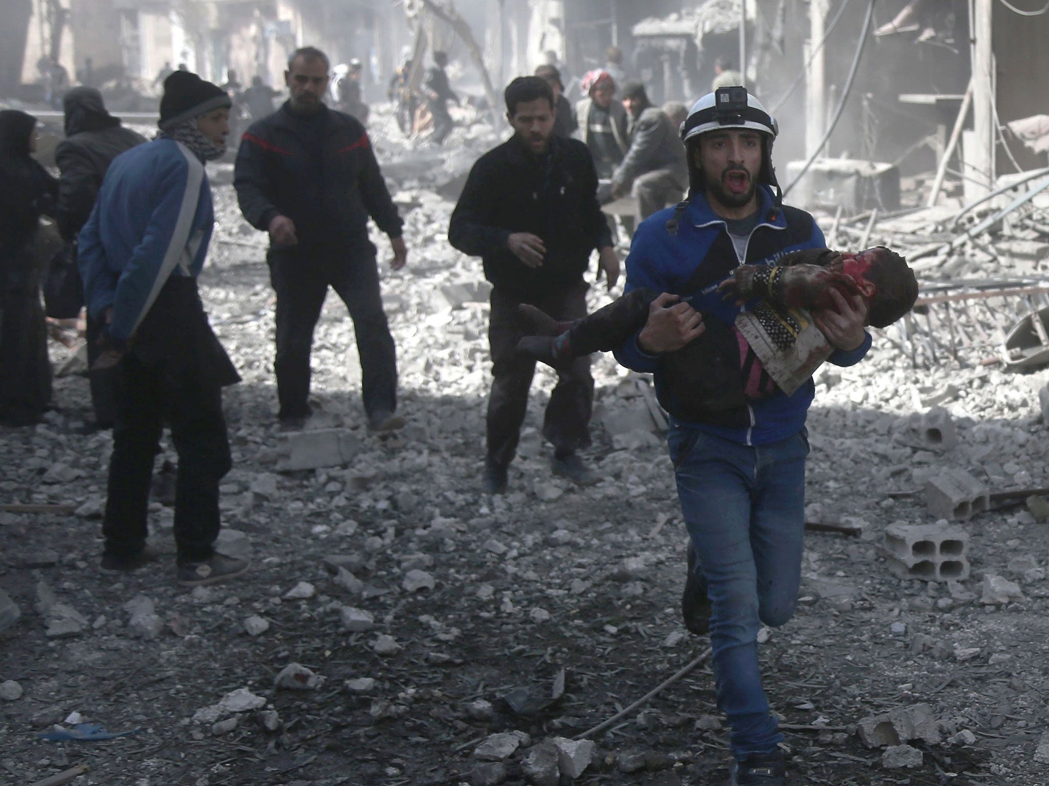 A Syrian civil defence member carries an injured child rescued from between the rubble of buildings following government bombing in the rebel-held town of Hamouria, in the besieged Eastern Ghouta region on the outskirts of the capital Damascus
