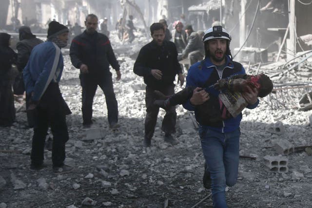 A Syrian civil defence member carries an injured child rescued from between the rubble of buildings following government bombing in the rebel-held town of Hamouria, in the besieged Eastern Ghouta region on the outskirts of the capital Damascus