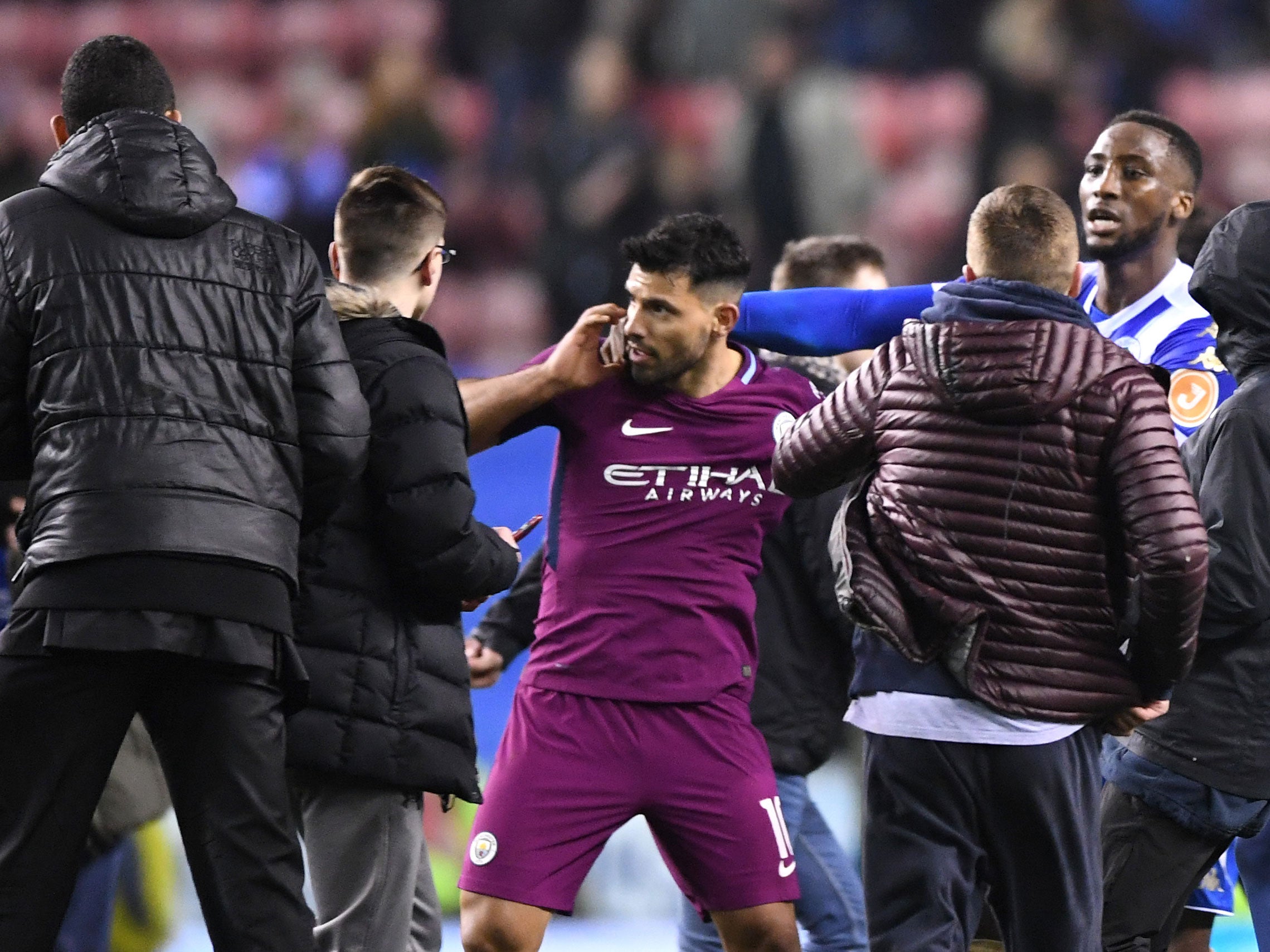 Wigan win over Manchester City marred by pitch invasion as Sergio Aguero clashes with fan