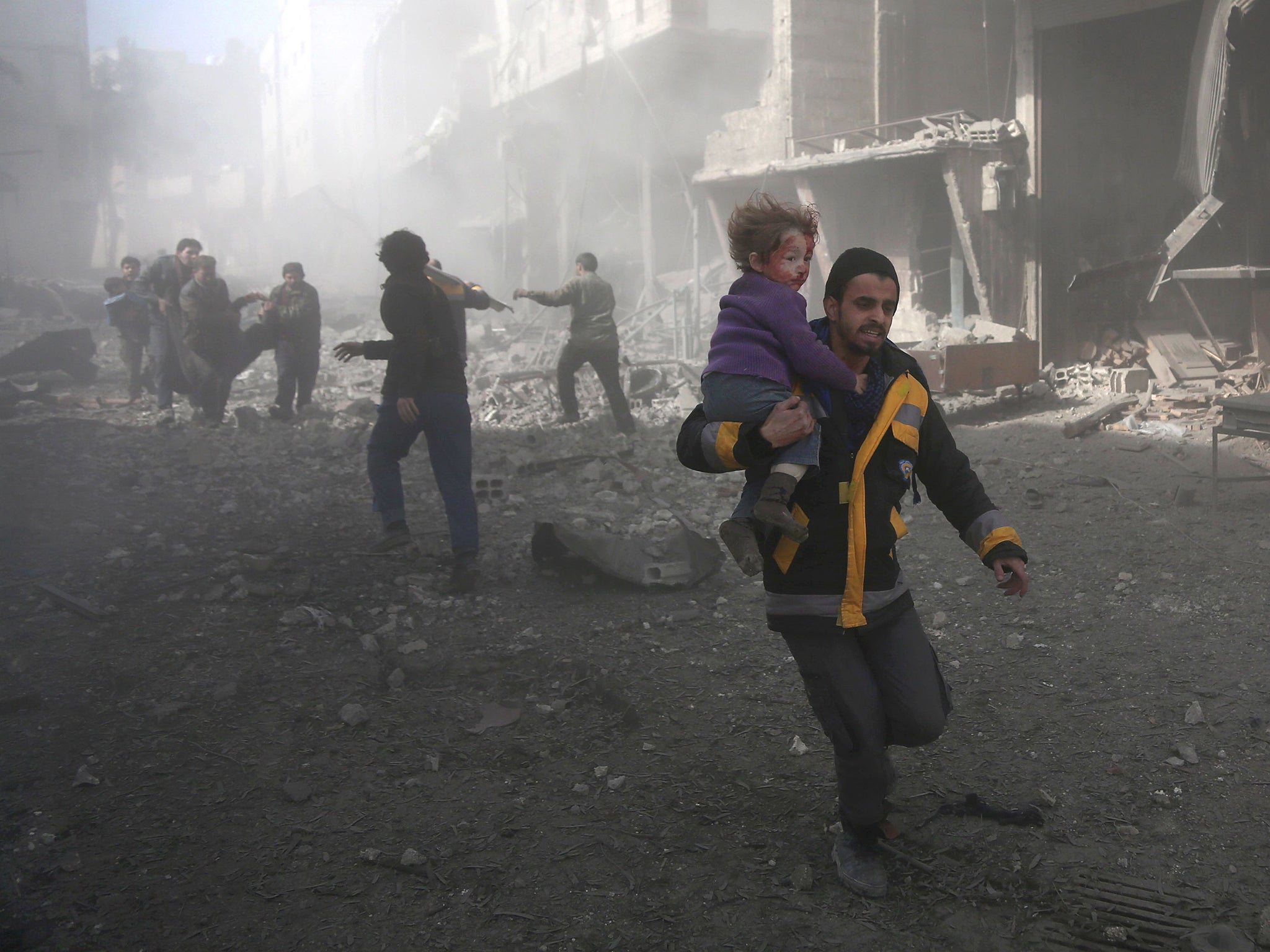 A Syrian man carries a child injured in government bombing in the rebel-held town of Hamouria, in the besieged Eastern Ghouta region on the outskirts of the capital Damascus (ABDULMONAM EASSA/AFP/Getty Images)