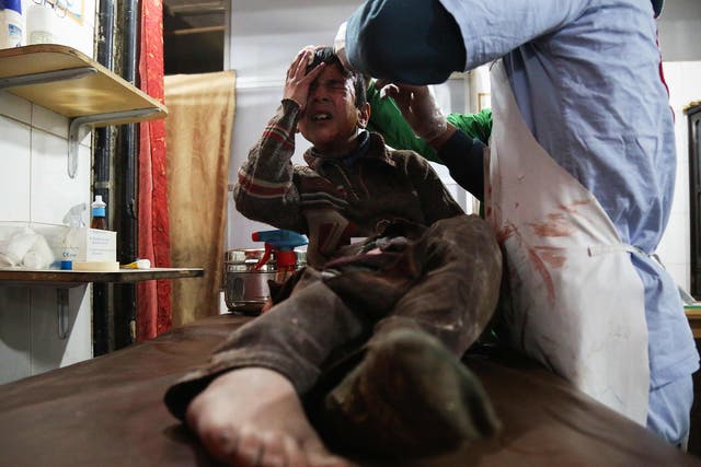 A wounded 12-year-old Syrian boy, cries as he receives treatment at a makeshift hospital on Monday