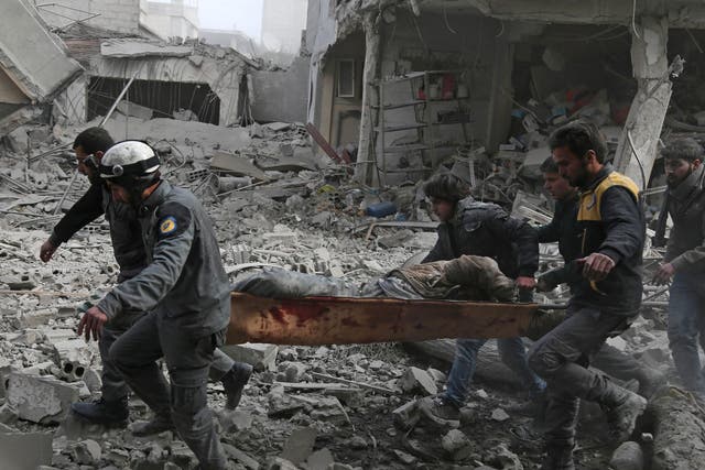 Members of the Syrian Civil Defence, also known as the White Helmets, evacuate an injured civilian on a stretcher from an area hit by a reported regime air strike in the rebel-held town of Saqba, in the besieged Eastern Ghouta region on the outskirts of the capital Damascus