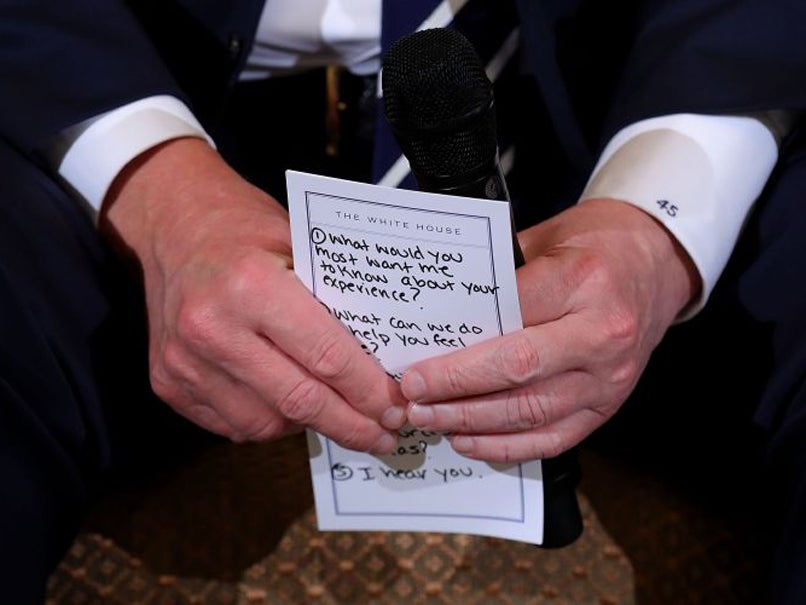 President Donald Trump holds his notes while hosting a listening session with students survivors of mass shootings, their parents and teachers in the State Dining Room at the White House