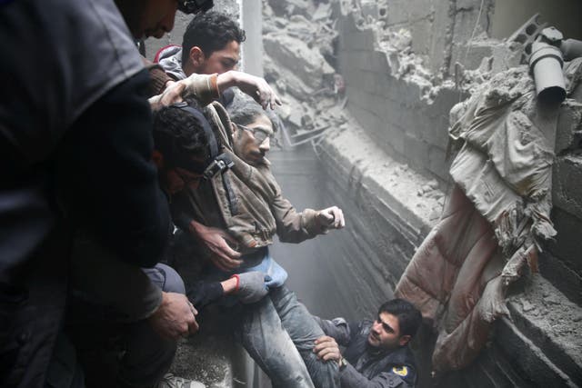 Civil defence rescue workers help a man from a shelter after an air strike in the besieged town of Douma in eastern Ghouta, 22 February 2018