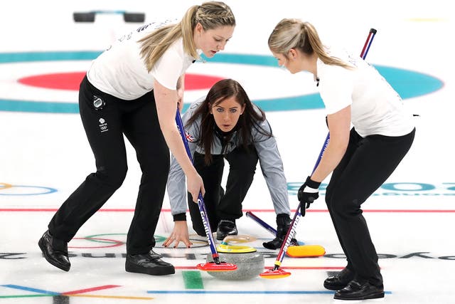 Lauren Gray, left, and Vicki Adams sweep the ice in front of a stone cast by Eve Muirhead