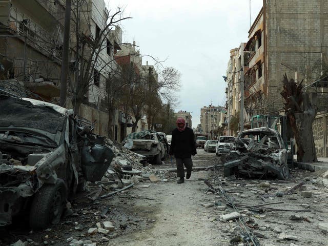 A Syrian man walks next to damaged buildings following regime air strikes in the Syrian rebel-held town of Douma, in the besieged Eastern Ghouta region on the outskirts of the capital Damascus
