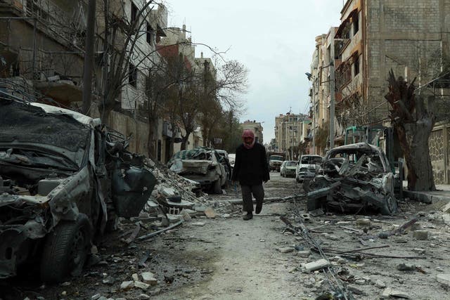 A Syrian man walks next to damaged buildings following regime air strikes in the Syrian rebel-held town of Douma, in the besieged Eastern Ghouta region on the outskirts of the capital Damascus