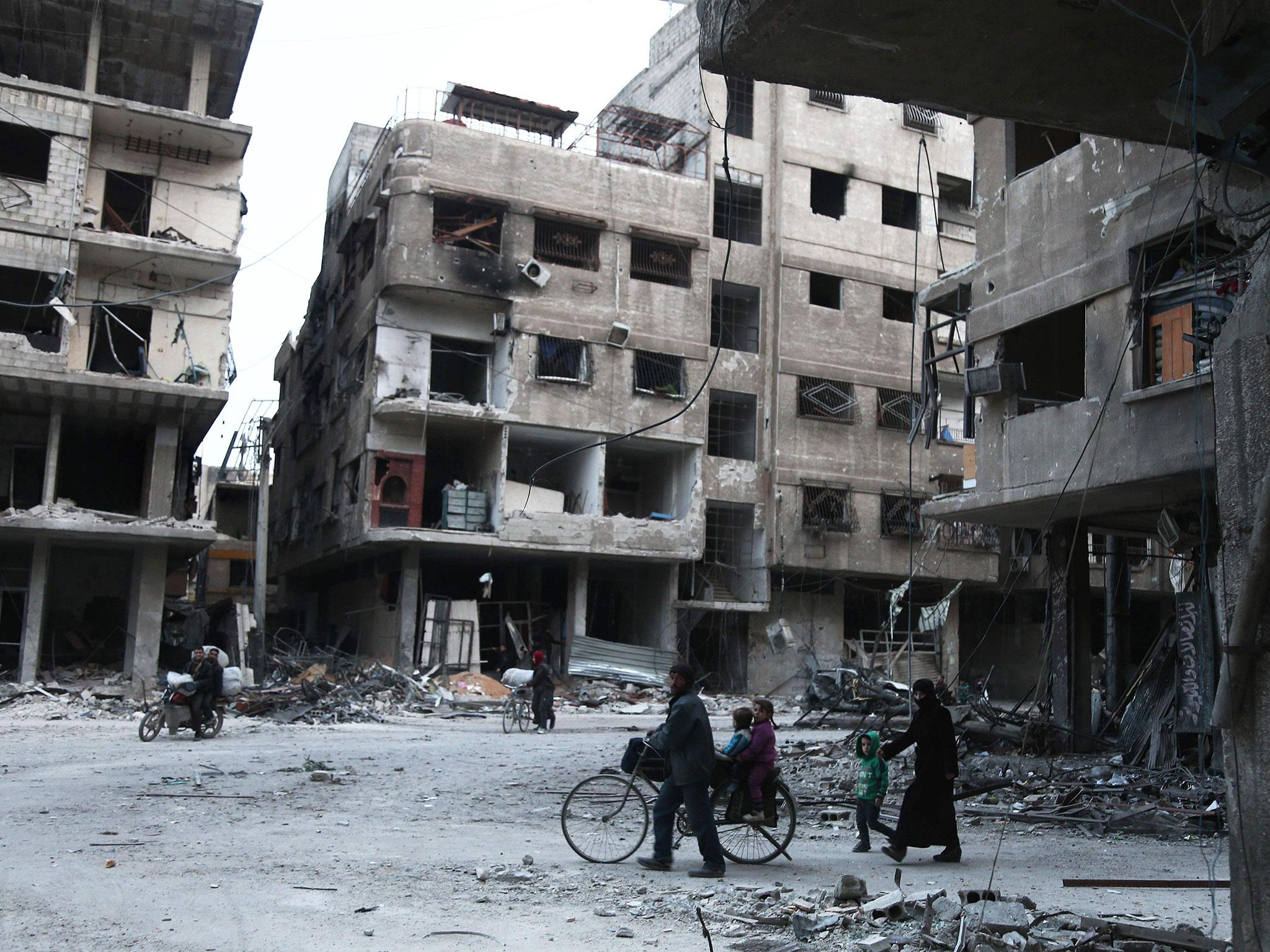 Syrians walk past destroyed buildings in Arbin in the rebel-held enclave of eastern Ghouta on Sunday