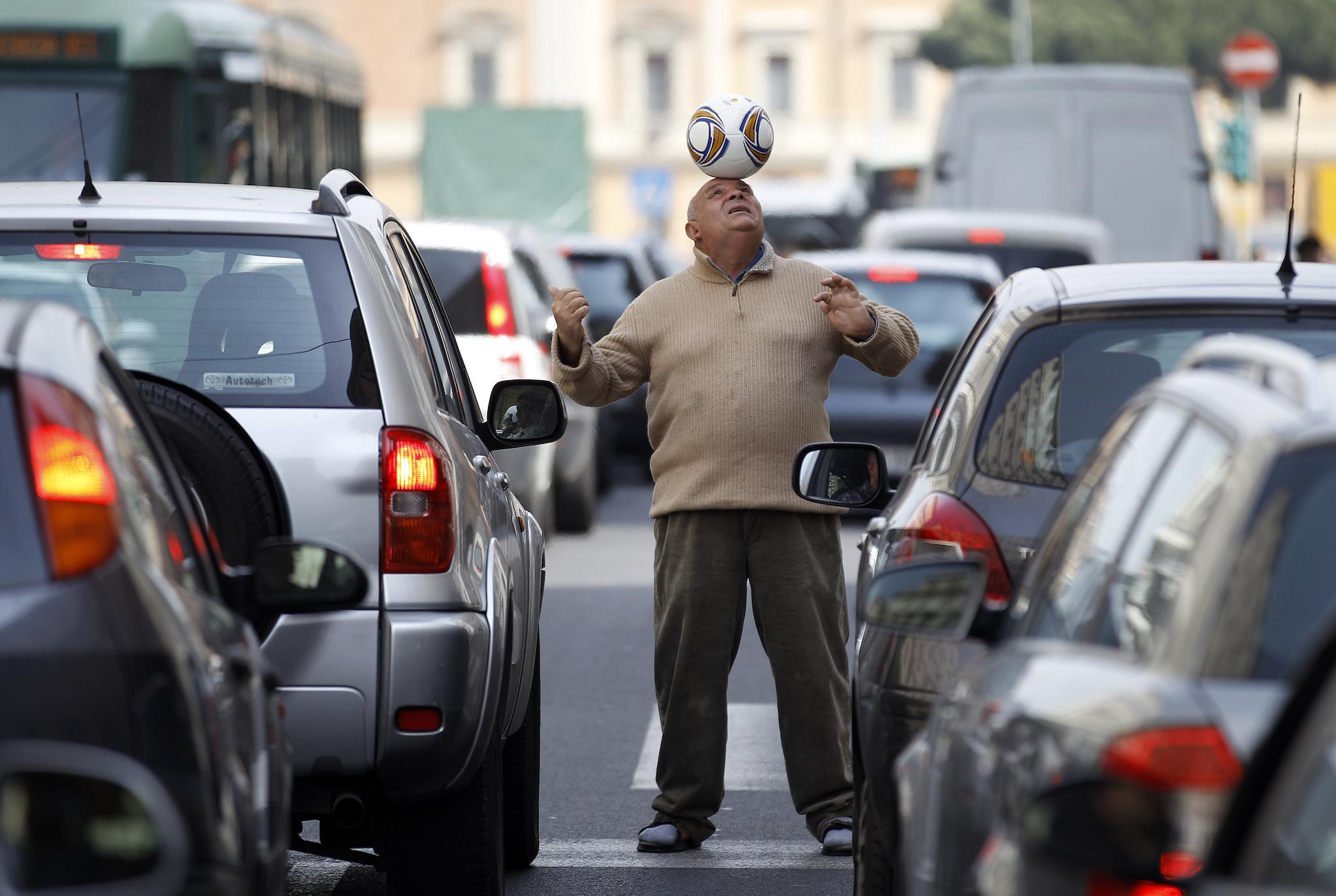 A man balances a soccer ball on his head amongst cars stopped in a traffic jam in Rome April 4, 2012