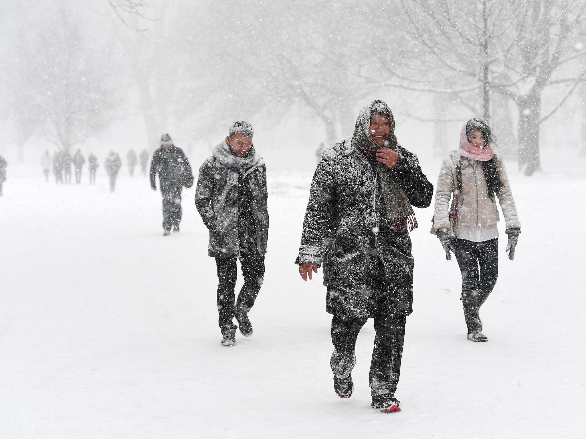 People walk through heavy snow in Green Park in central London