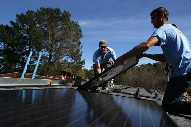 Workers install a solar panel on the roof of a home in San Rafael, California.