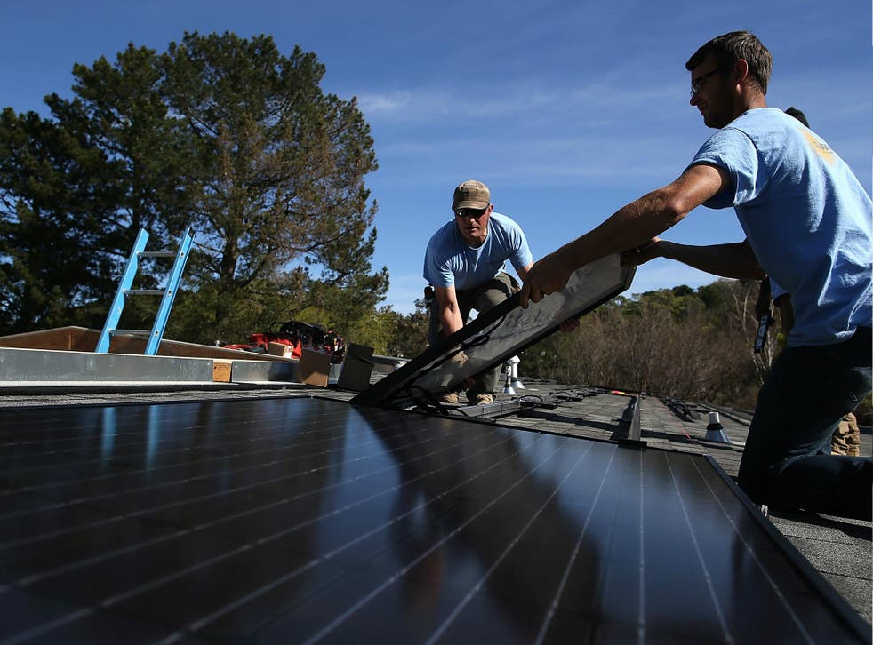 Workers install a solar panel on the roof of a home in San Rafael, California.
