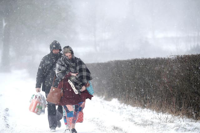 A couple walk along the A53 Buxton Road, which is closed due to heavy snow fall, after abandoning their car near Leek