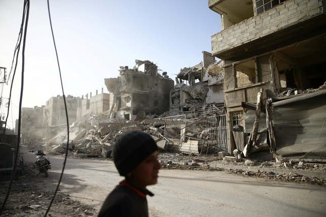 A boy walks near damaged buildings in the besieged town of Douma in Eastern Ghouta on Thursday