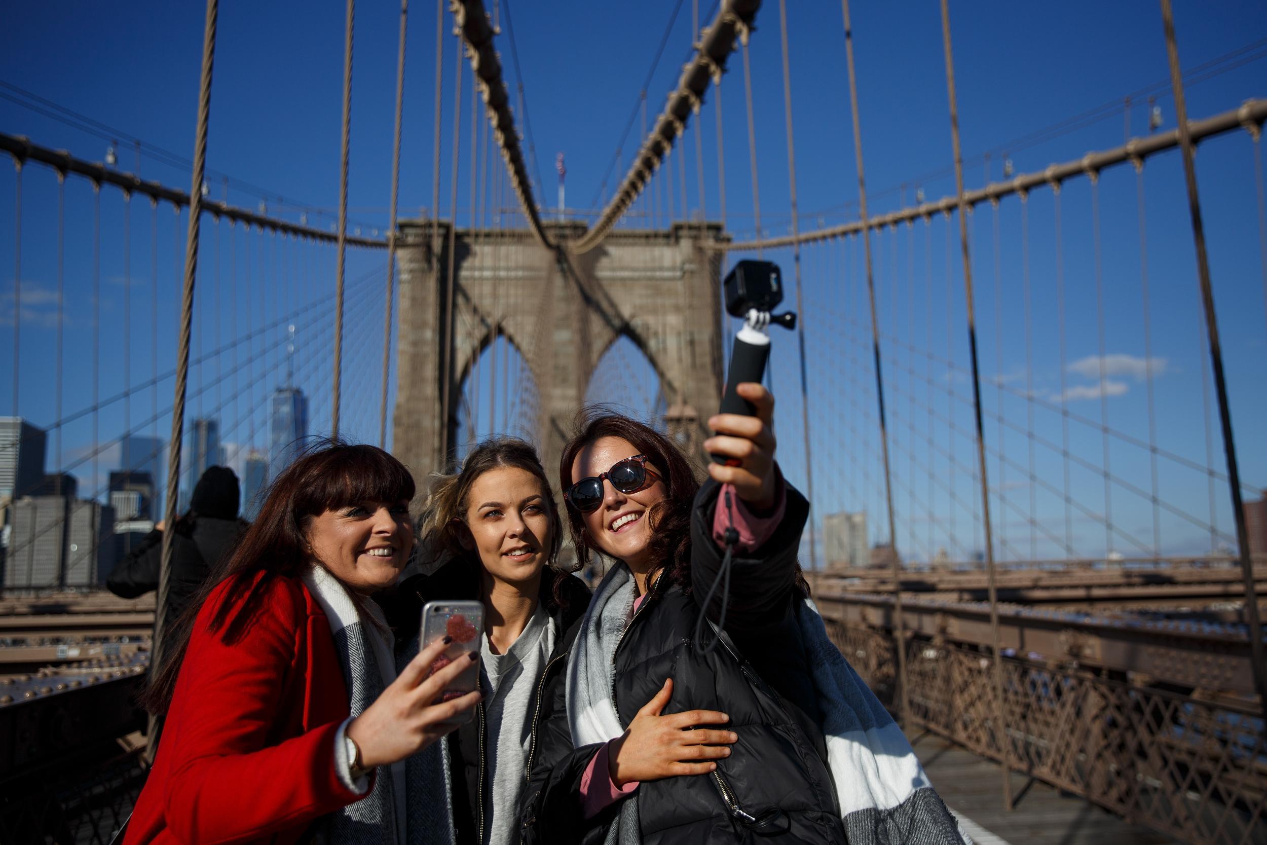 A group of friends takes a photograph on the Brooklyn Bridge