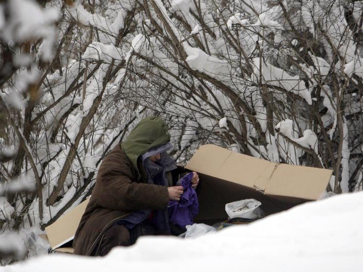 A homeless man tries to warm up in a snow covered park in Prague. The Czech Republic has recorded six deaths linked to the cold weather.