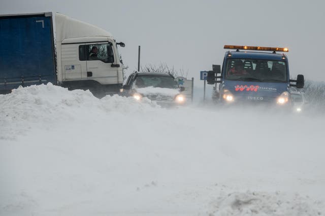 Vehicles attempt to drive through drifting snow that has formed on the A46, near Bath