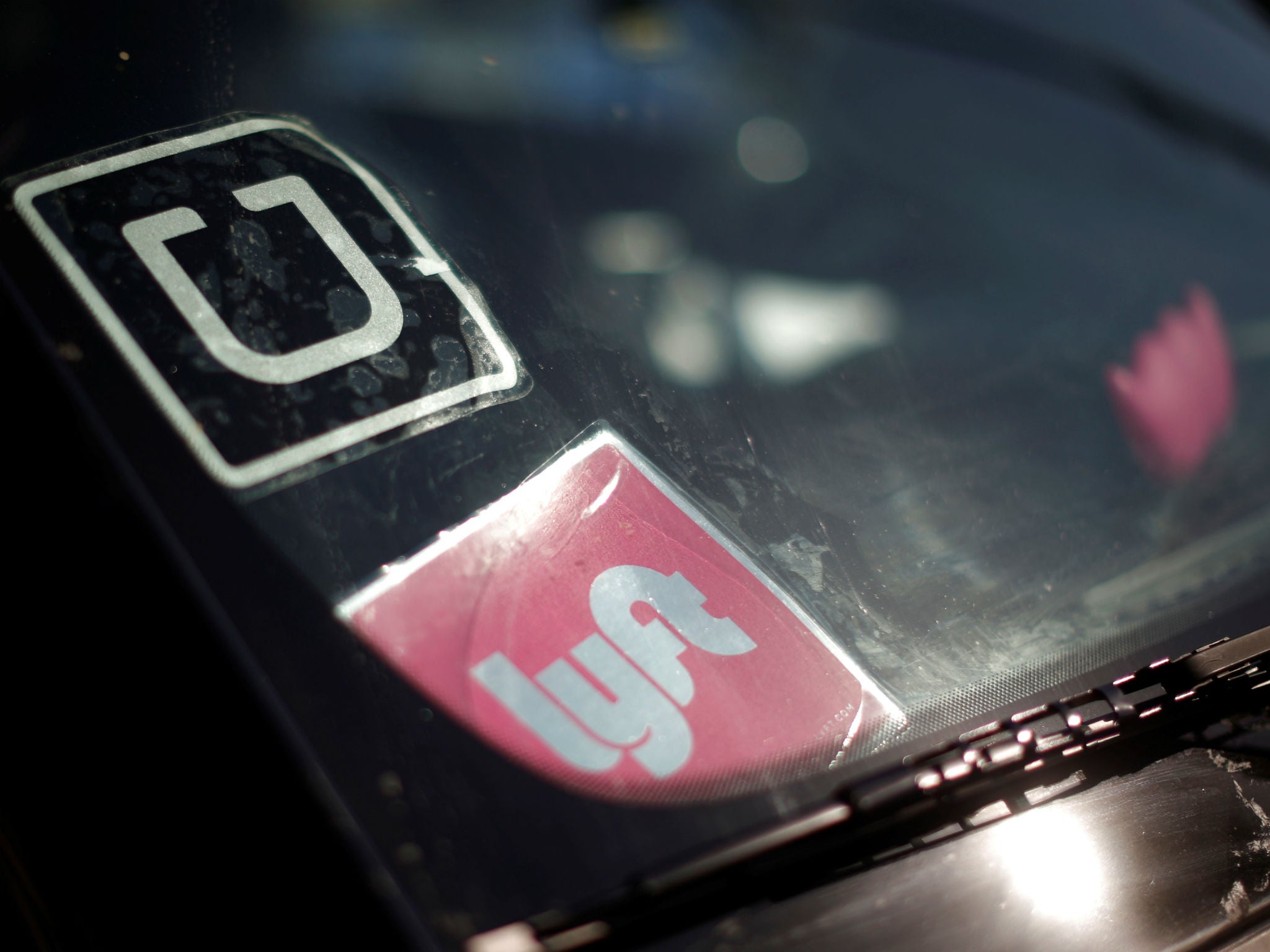 A driver displays Uber and Lyft ride sharing signs in his car windscreen