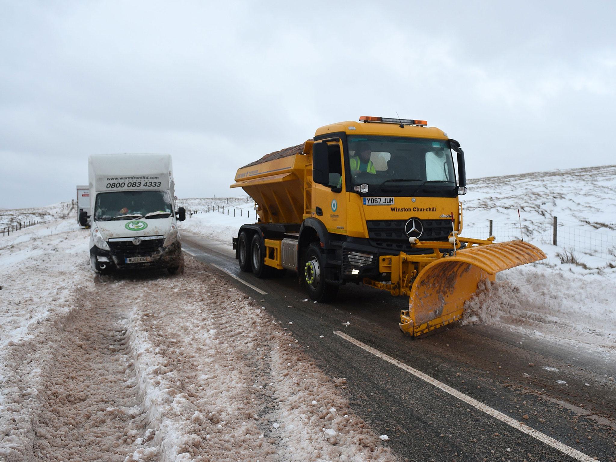 A gritter lorry passes an abandoned van on the A672 near the M62 motorway in Manchester